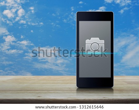 Camera flat icon on modern smart mobile phone screen on wooden table over blue sky with white clouds, Business camera shop online concept