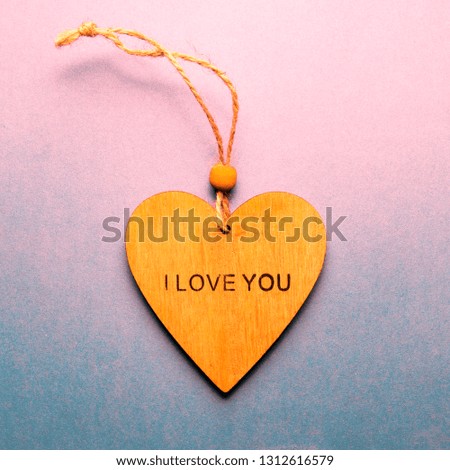 A wooden heart with the words "I love you", flat lay on gradient pink background, space for your records