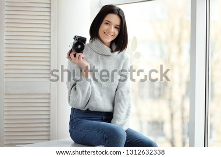 girl with a camera sitting by the window