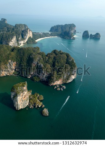 Photo from drone of Ao Nang beach, Krabi, Thailand. Boats float around the green rocks.