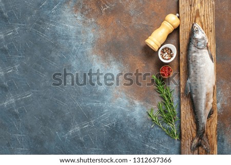 Cutting of a salmon  on a wooden board. Preparation of raw fish with spices. Top view. Copy space
