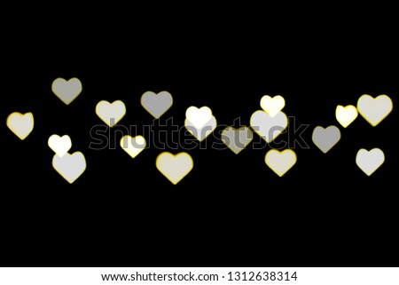 Beautiful yellow and white bokeh on a black background. Can be used as a background or wallpaper. Heart shape. Love Concept, Valentine's Day.