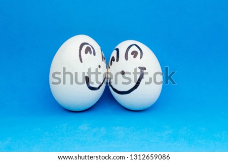 Two white eggs smile at each other. Painted faces and emotions