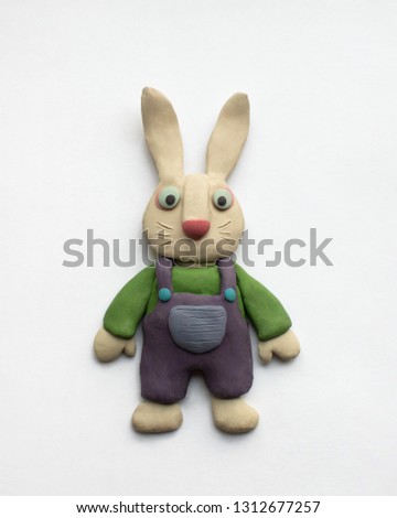 Little bunny in overalls. Plasticine easter character on a white background Royalty-Free Stock Photo #1312677257