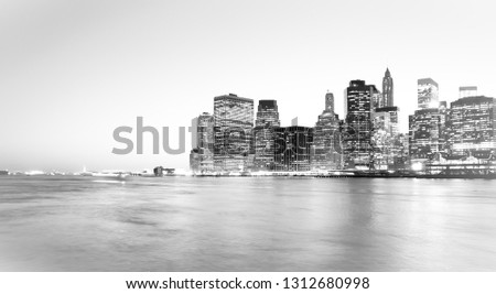 Panoramic view of New York Financial District and the Lower Manhattan at night viewed from the Brooklyn Bridge Park. High key black and white image.