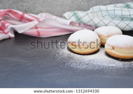 The so-called Krapfen, which are traditionally baked in Germany during the carnival season, lie on a dark surface - donuts sprinkled with powdered sugar