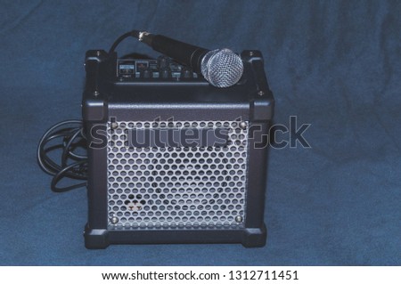 Small-sized  microphone and portable combo amp for guitar, singing, or harmonica on a black background suitable for outdoor performances street musica