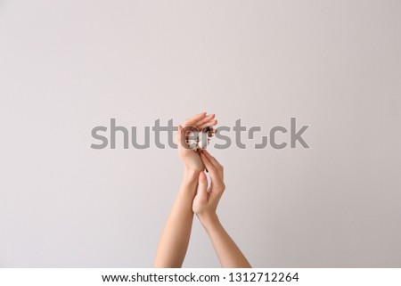 Female hands with cotton flower on light background