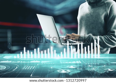 Young hacker using laptop with forex chart on blurry office interior background. Trade, innovation and hacking concept. Double exposure 