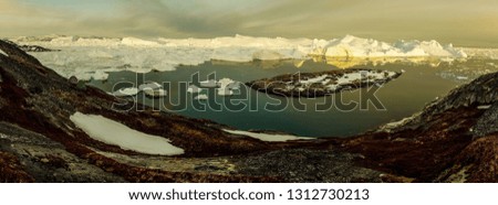Golden hour winter and glacier ice fjord landscapes near Ilulissat in Greenland during midnight sun.