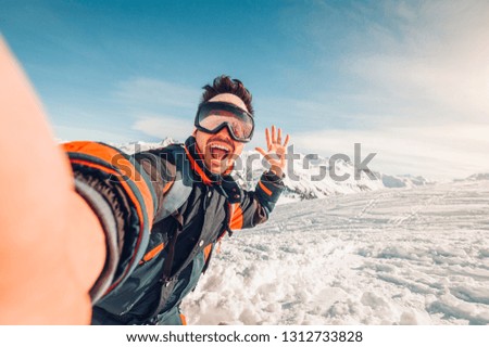 Happy caucasian man taking a selfie hiking a mountain full of snow at winter. Portrait of a skier at vacation