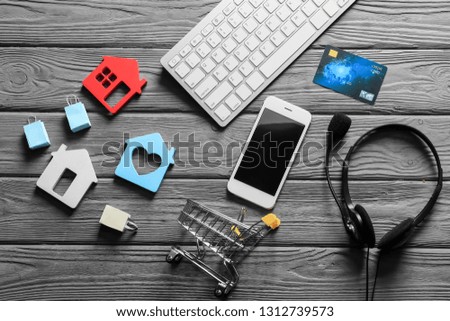 Composition with small cart, computer keyboard and mobile phone on wooden background. Online shopping