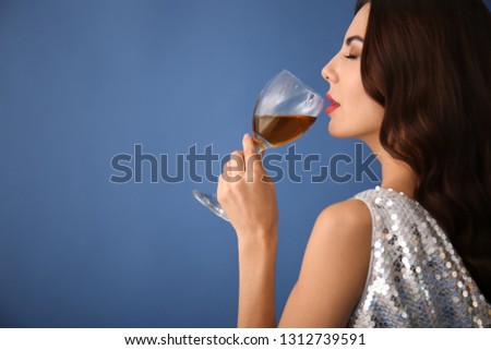 Beautiful young woman with glass of wine on color background