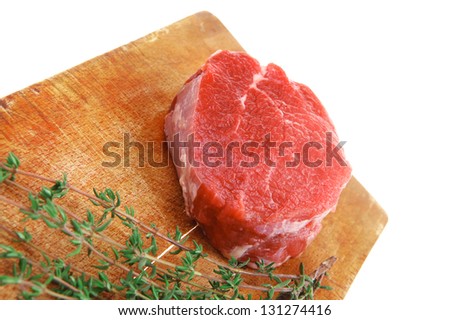raw red meat : fresh beef single fillet chop with thyme on wooden plate . isolated over white background