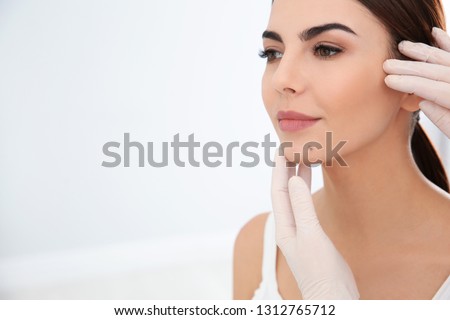 Dermatologist examining young patient's birthmark in clinic. Space for text Royalty-Free Stock Photo #1312765712