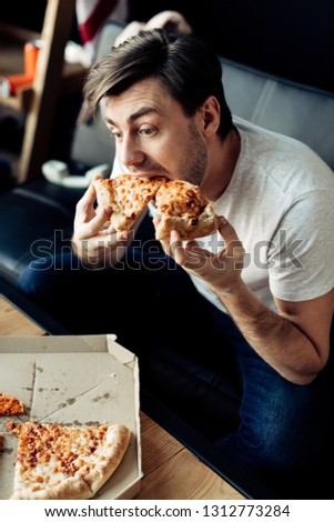 hungry man eating tasty pizza in living room
