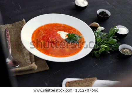 Traditional Ukrainian Russian borsch with sour cream and white beans on a dark background. Red vegetable beetroot soup. Outside observer.