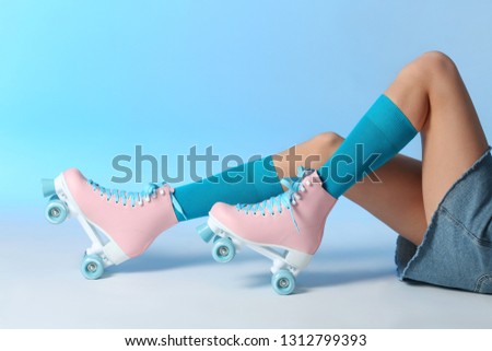 Woman with vintage roller skates on color background, closeup