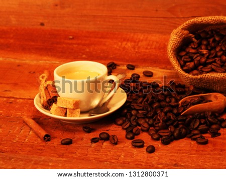 White Hot Coffee cup with Coffee beans, burlap sack and with cinnamon sticks on the wooden table