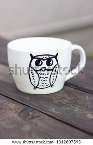 White ceramic mug with permanent marker drawing on wooden table diy handmade cup gift with owl picture
