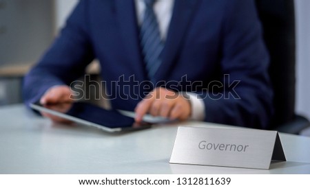 Governor working on tablet pc, analyzing political statistic information, work