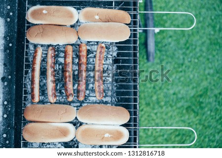 top view of tasty hot dogs grilling on bbq grill grade on green grass background