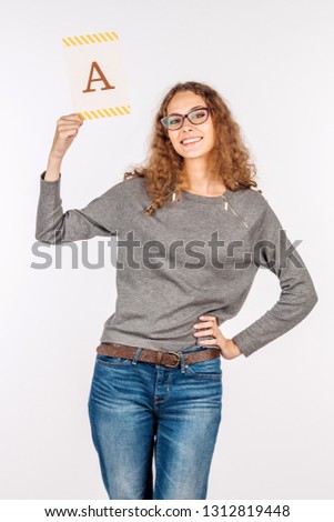 young beautiful woman holding a blank white paper with the letter A.