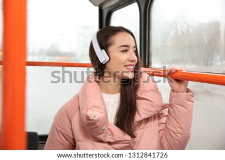 Beautiful young woman listening to music with headphones in public transport