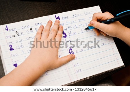 child doing homework. school task, hand writing exercise. learning to write number  names. 