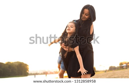 Young mother and daughter playing and walking on sandy beach