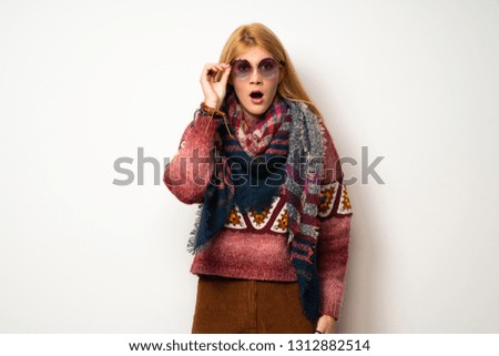 Hippie woman over white wall with glasses and surprised