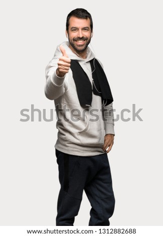 Sport man giving a thumbs up gesture because something good has happened over isolated grey background