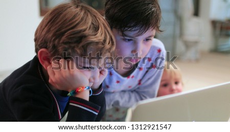 Children hypnotizd by screen, young boys watching cartoon content online starring at screen