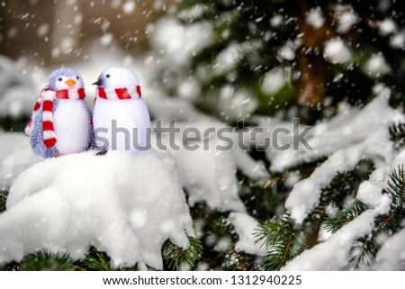 Two decorative penguins sit on the snow 