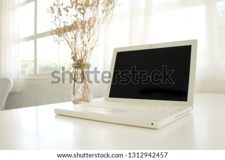 Mock up Laptop on a blank screen on a white table, window backdrop and natural light