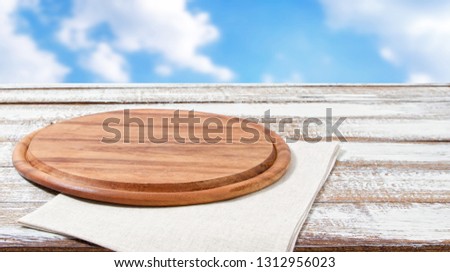 empty pizza board on empty wooden table with tablecloth,napkin - top view