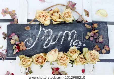 Mum handwritten on a slate chalk board surrounded by dried roses and hydrangea petals , a vintage style shabby chic floral style image for mothers day or a birthday 