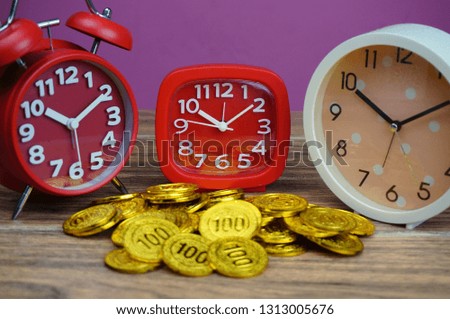 Conceptual photo of important of time and investment by using clocks and wooden table. Selective focus.
