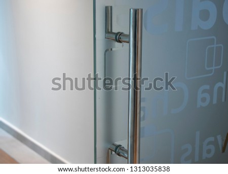 Glass door with metal handle and signs in office building
