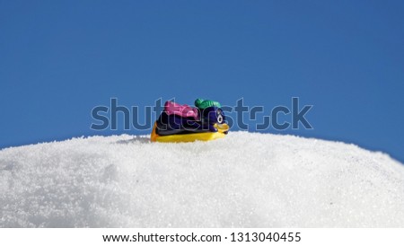 a toy penguin with a yellow slide on snow