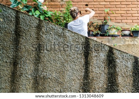 Young blond woman in her 30s taking care of the garden