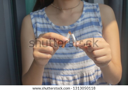 Close up of woman breaking cigarette in half. Quitting smoking habit