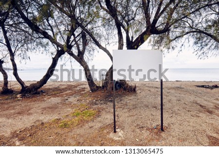 Blank empty white sign post on the beach near the sea on a seaside background 