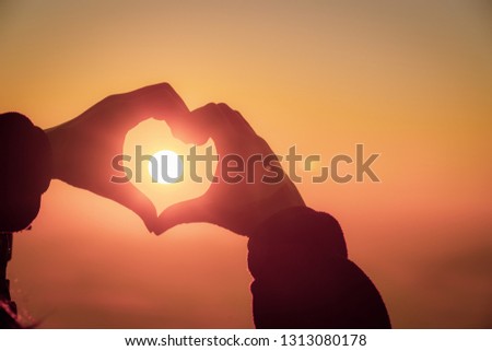 Female hands in the form of love with the sun in the heart