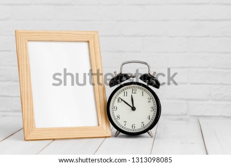 Photo frame and alarm clock on white wood table with copy sapce.