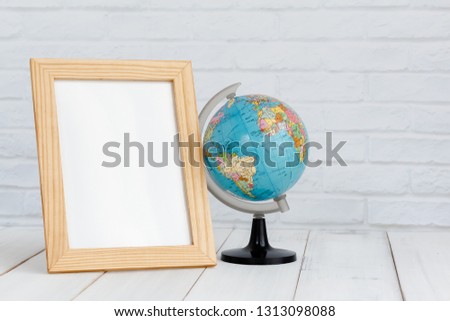 Photo frame and globe on white wood table with copy sapce, travel concept.