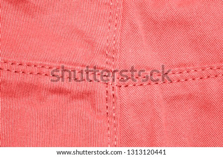 The texture material jeans of the fabric is pink with seams. Living coral - color 2019 pantone. 