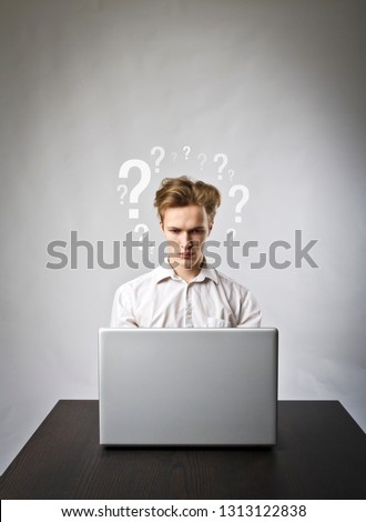 Young man using a laptop to browse the net. Questions and troubles concept.