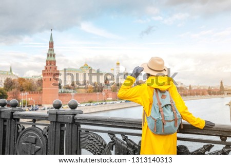 Happy asian woman tourist on the background of the Kremlin wall tower from the Moscow river embankment. Travel in Russia concept