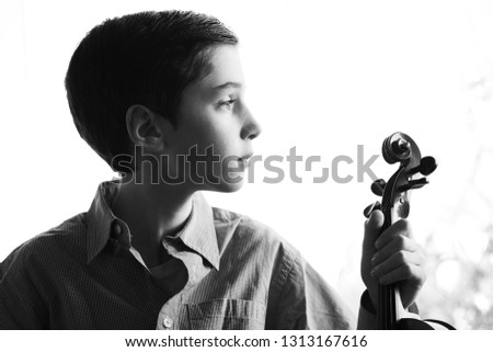 Portrait of a young boy holding a violin in a melancholic attitude, profile, black and white photography